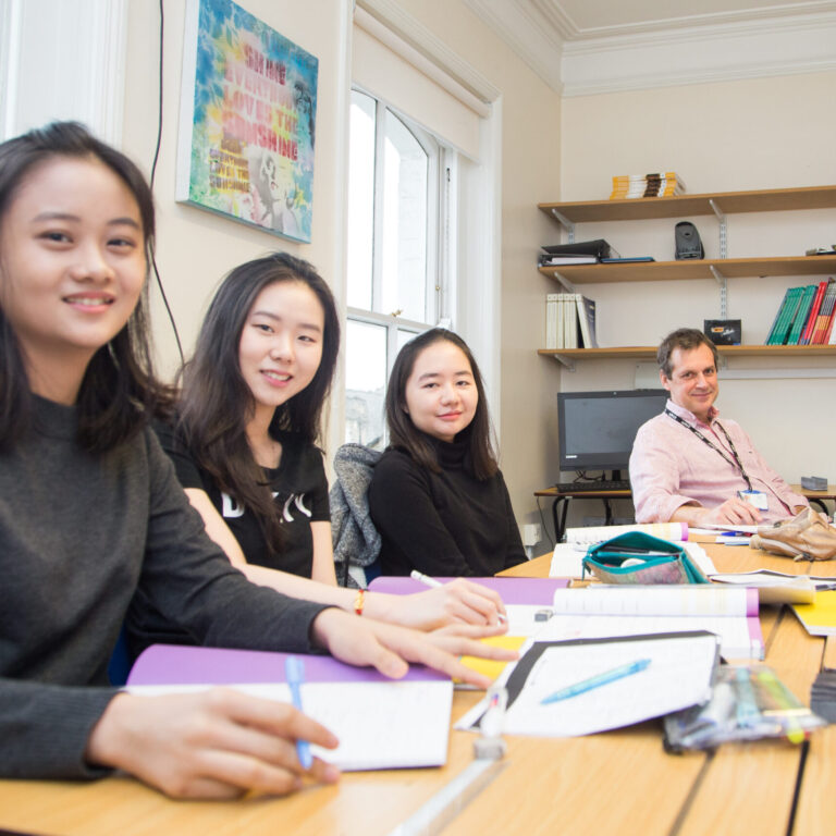 three school students and their teacher sitting at a desk