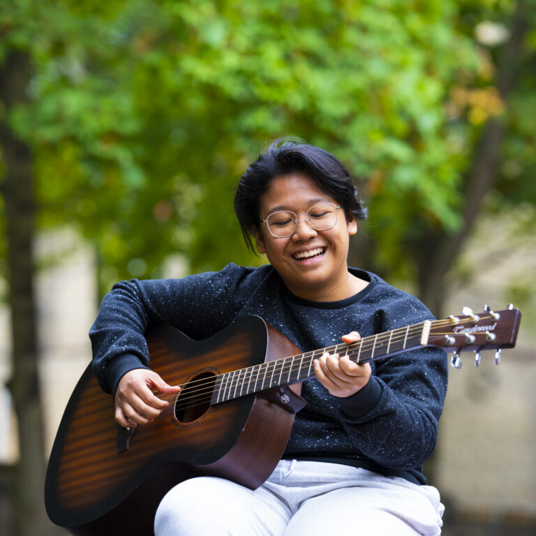 student playing the guitar outside