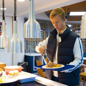 student placing a jacket potato on a plate