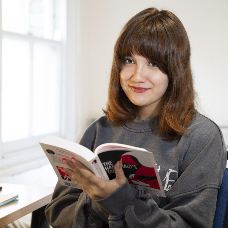 girl in her dorm room reading a book