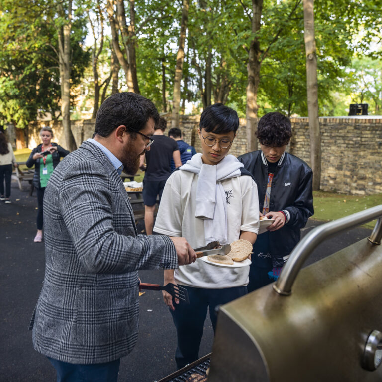 man giving a student a patty from the grill